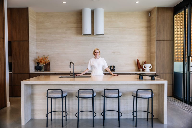 Woman standing at a travertine kitchen island in a newly built family home