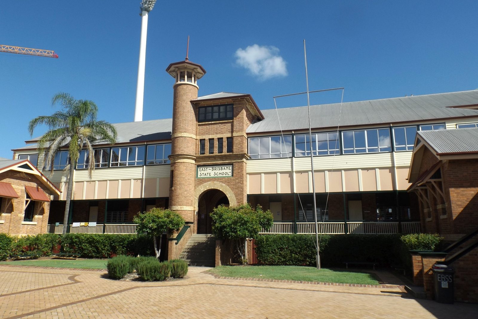 East Brisbane State School's brick entrance tower, with a Gabba light tower behind