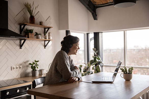 happy-woman-video-chatting-on-laptop-in-kitchen